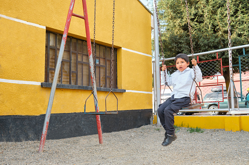 latino child playing on the swing in an outdoor park in la paz bolivia