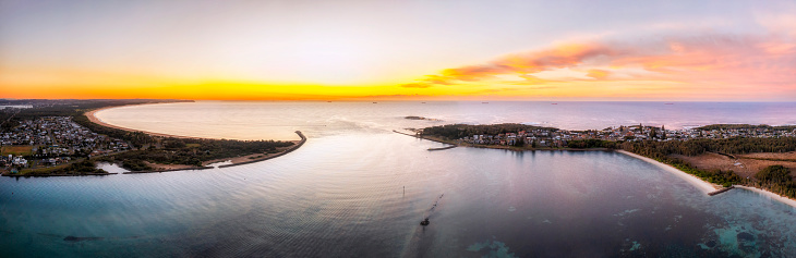 Swansea channel entering Pacific ocean new Newcastle city connecting Lake Macquarie at sunrise in aerial panorama.