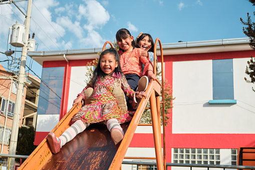 three latin girls playing on the slide in an outdoor park in bolivia latin america