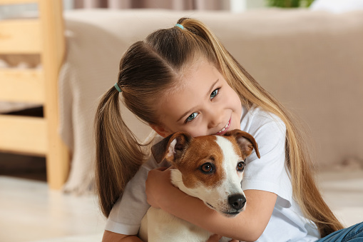 Cute girl hugging her dog at home. Adorable pet