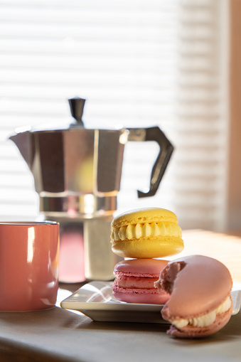 Stack of pastel macarons with espresso at brunch.