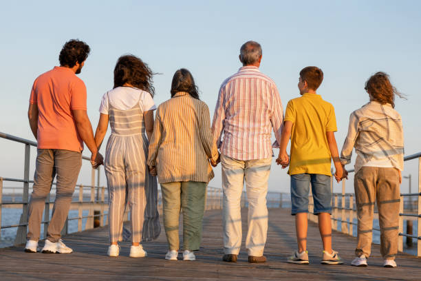 istock Caucasian multi-generation people hold hands, relax, enjoy walk on sea pier, back 1786475859