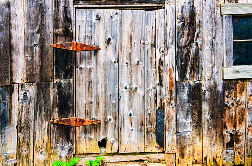 Rusty iron hinges and weatherworn wood on a side door of an old barn in central Vermont.