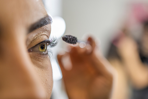 Make-up artist at a beauty salon using mascara on a beautiful young woman