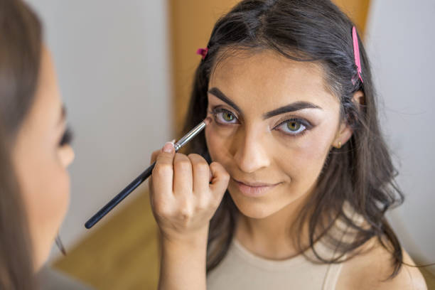 istock Makeup artist applying the eyeshadow under eye, with a brush on a female client in the make up studio. 1786501086
