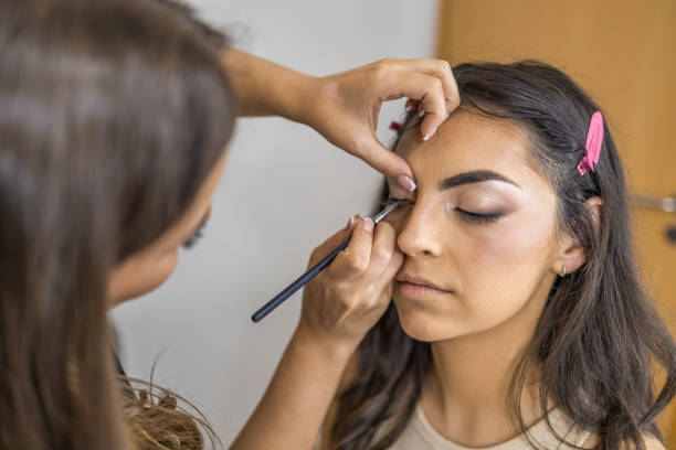 istock Makeup artist applying the eyeshadow, with a brush on a female client in the make up studio. 1786501605