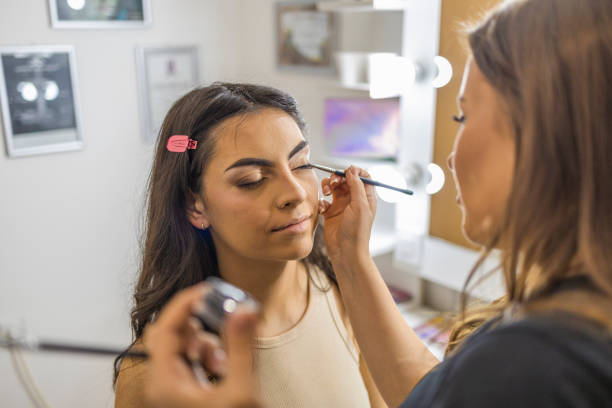 istock Makeup artist applying the eyeshadow, with a brush on a female client in the make up studio. 1786502119