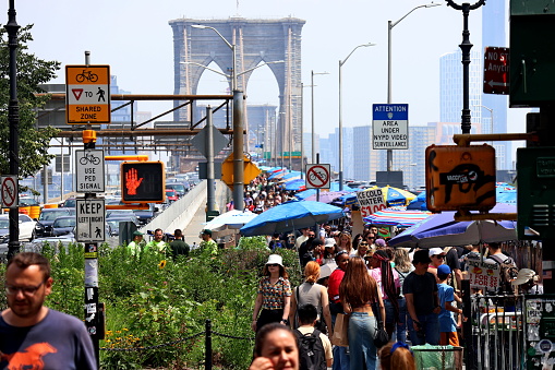Street fair on Brooklyn Bridge, people selling things from stands with umbrellas