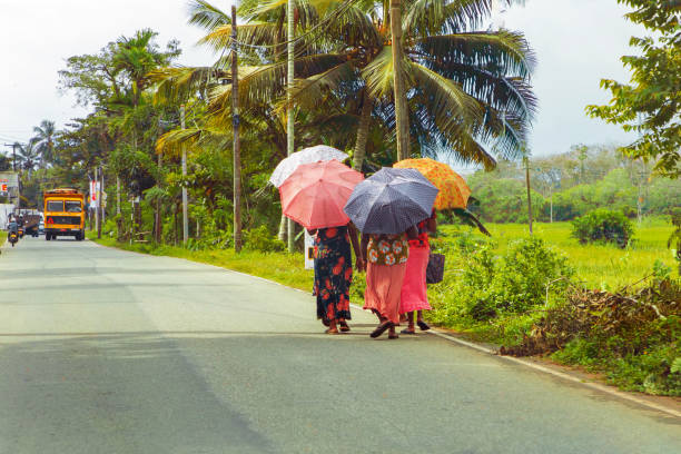 Polonnaruwa, Sri Lanka. 02 February 2023. unrecognizable people in colorful bright clothes under sun umbrellas walk along road