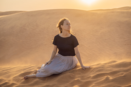 Young beautiful woman traveling in the desert. Sandy dunes and blue sky on sunny summer day. Travel, adventure, freedom concept. Tourism reopens after quarantine COVID 19.
