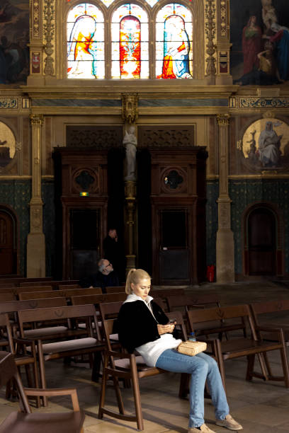 Paris, France: Tourist Resting Inside Church of Saint-Eustache Paris, France: A tourist resting on a pew inside the inside the Church of Saint-Eustache, a Gothic structure completed in 1637 and located in the 1st arrondissement. église saint eustache stock pictures, royalty-free photos & images