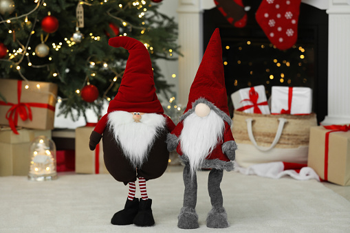 Funny Christmas gnomes on floor in decorated room