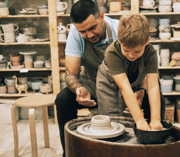 istock Confident handsome man and little boy making ceramic pot on the pottery class 1786610437
