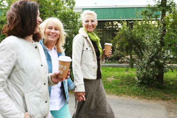 istock Three cheerful pensioners are walking in the park, having fun talking and drinking coffee. 1786615281