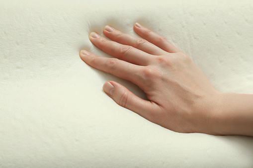 Woman touching orthopedic memory foam pillow, closeup