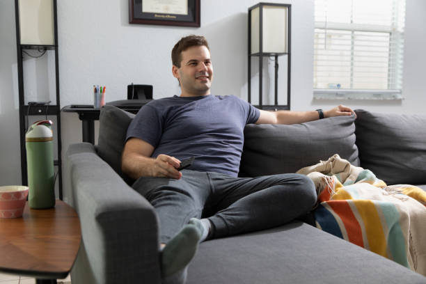 istock Young man watching tv on a sofa in the house 1786648836