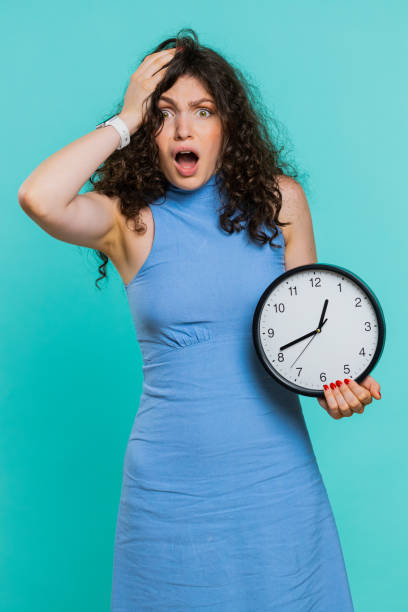 młoda kobieta z lękiem sprawdza czas na zegarze, spóźnia się do pracy, jest spóźniona, deadline - checking the time time clock women zdjęcia i obrazy z banku zdjęć