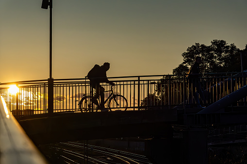 Stockholm, Sweden Oct 4, 2023 A bicyclist crosses a pedestrian bridge on the island of Sodermalm at sunset.