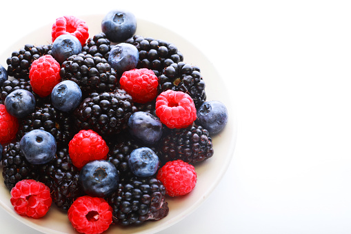 Various berries in a white plate. Blueberries, blackberries and raspberries are delicious diet berries.
