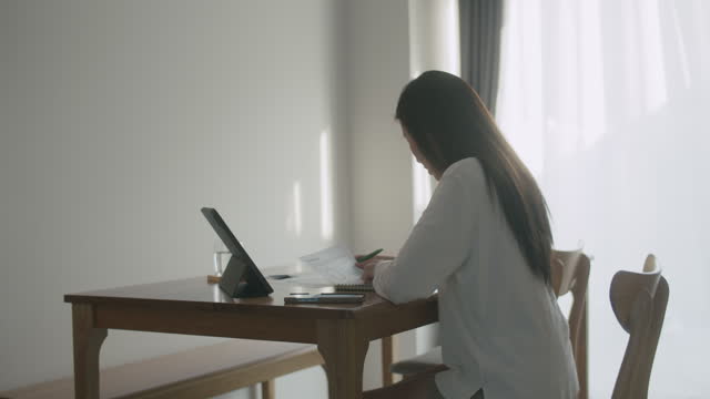 Young Asian woman working at home and calculating a budget income and expenses for personal finance.