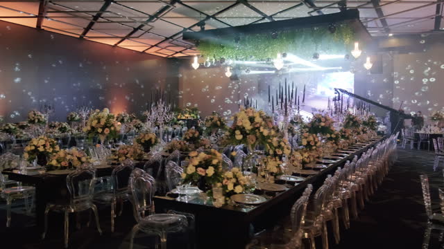 Table setting and bride and groom table at a wedding banquet decorated with flowers