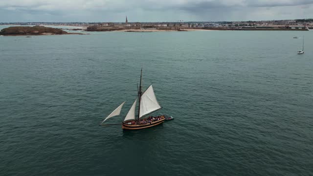 Le Renard wooden corsair ship sailing along Saint-Malo coast, France. Aerial drone view