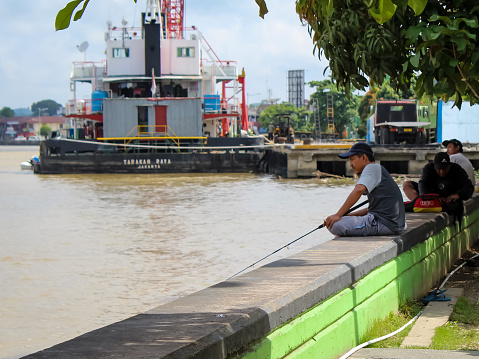 October 18, 2023 : the atmosphere of Segah River bank in East Borneo, Indonesia at the morning before noon with several people fishing leisurely.