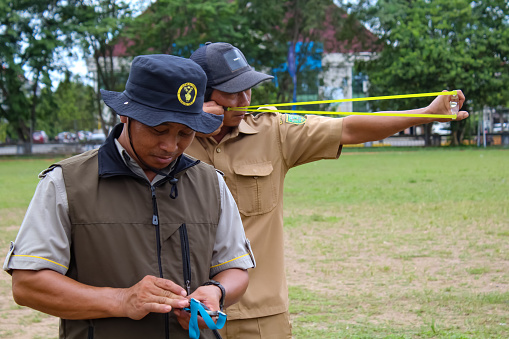 East Borneo, Indonesia - September 20, 2023 : Men playing Ketapel (catapult), a traditional slingshot.
