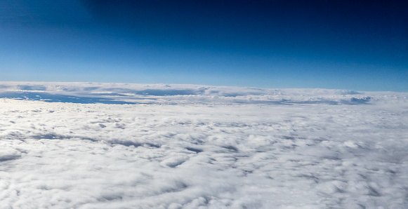 Aerial View above clouds in the Sky from an Airplane