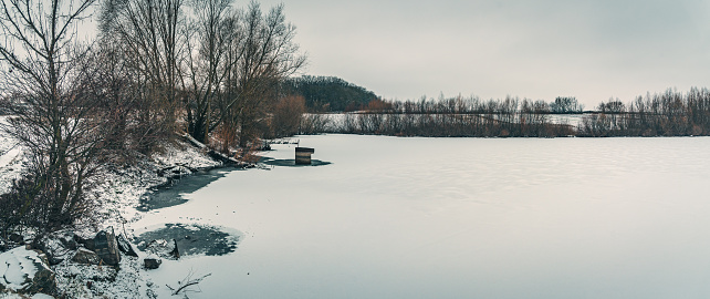 Just a photo of fields and river shores under light anow in snowfall