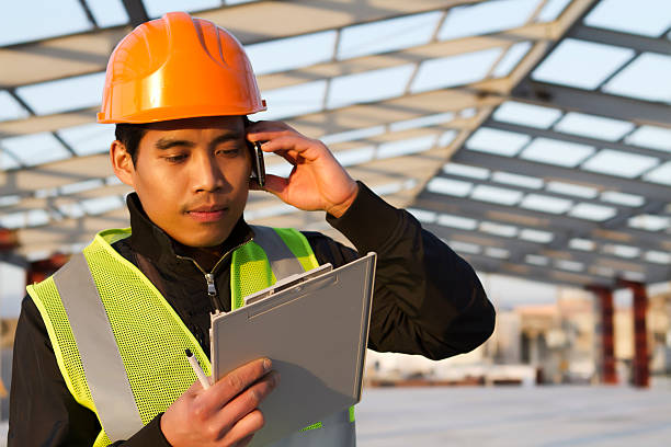 engenheiro de construção falando telefone móvel em novo edifício - civil building imagens e fotografias de stock