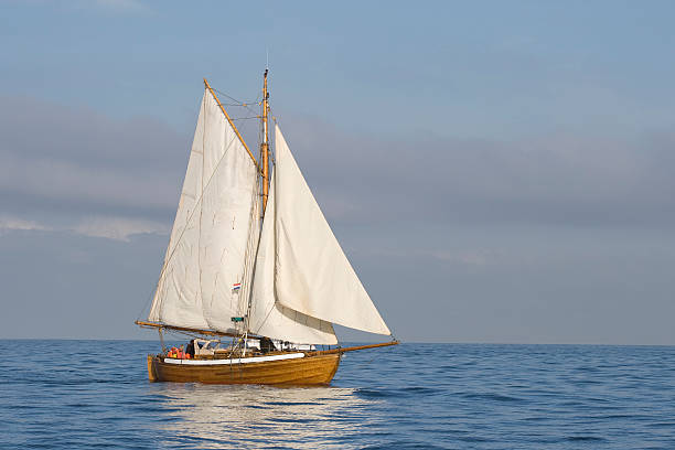 Tender with white sails Tender with white sails in the calm sea gaff sails stock pictures, royalty-free photos & images