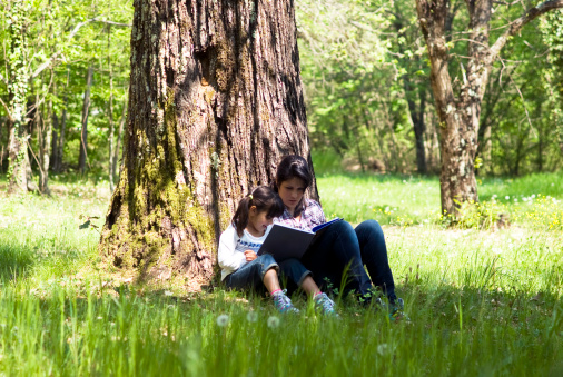 Girls sitting under tree reading a book