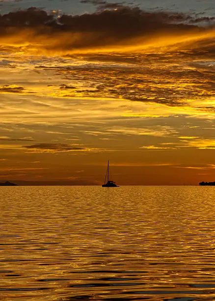 Colorful sunset in the lagoon of Bora Bora. A sailing boat at the horizon.