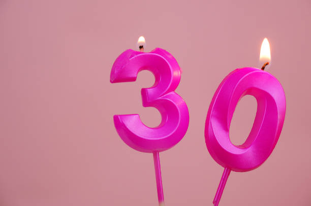 istock Pink birthday candles burning on pink, number 30, room for text. 1787077389