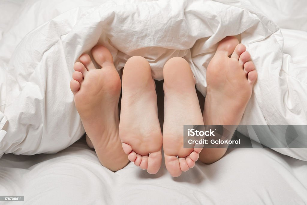 Feet in a bed Close up of four feet in a white bed Adult Stock Photo