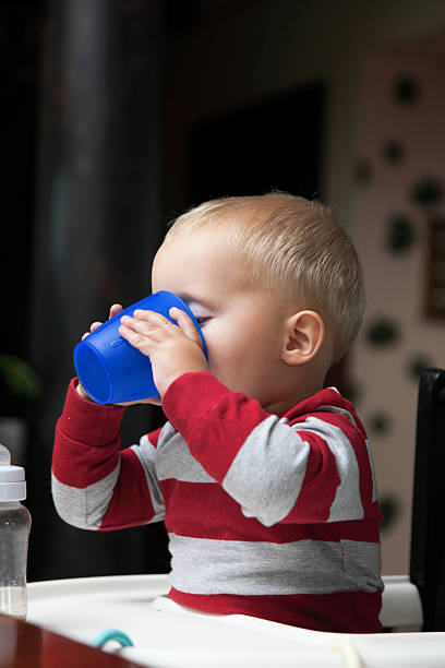 bambino ragazzo giocando con bottiglia e boccale indoor - baby cup foto e immagini stock