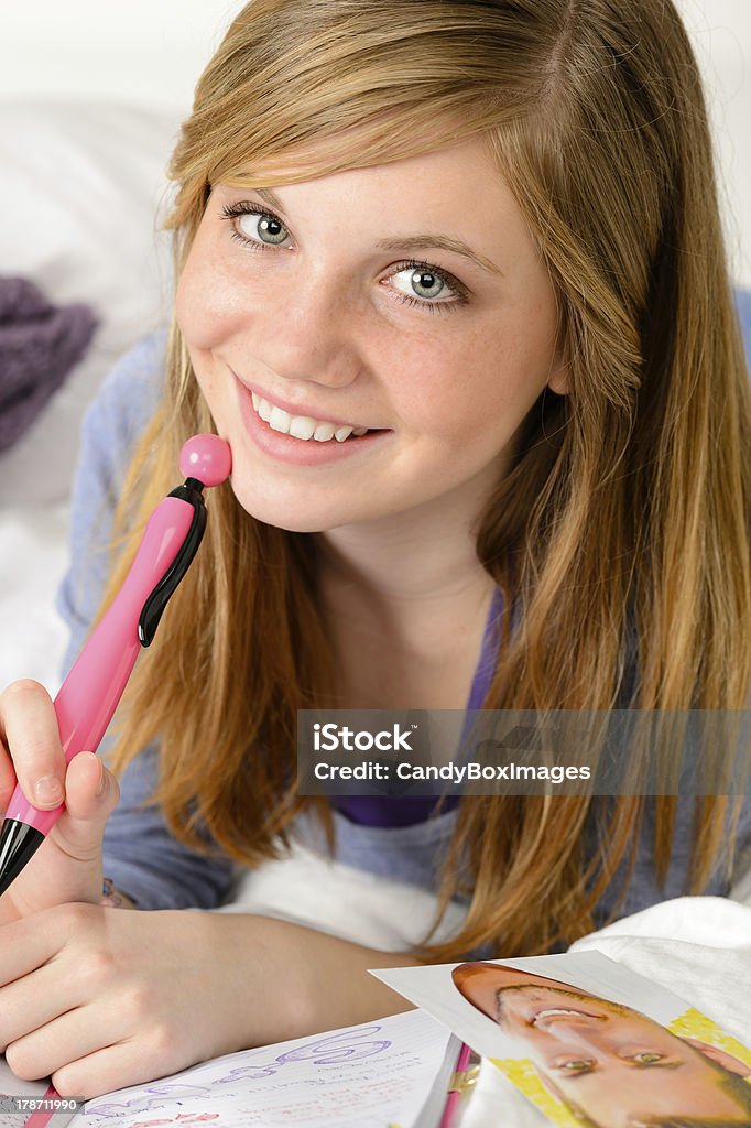 Smiling teenage girl daydreaming over her diary Smiling teenage girl daydreaming about love over her diary Adolescence Stock Photo