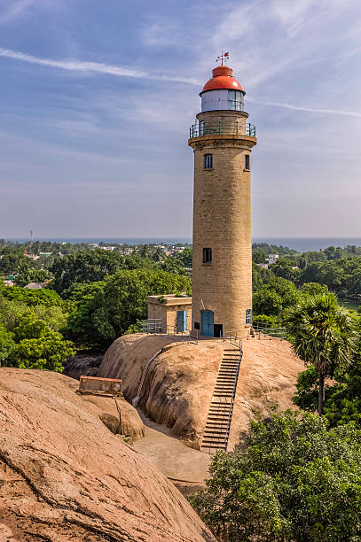 The modern lighthouse, Mamallapuram, Tamil Nadu, India. A view of the modern lighthouse constructed on the base of a huge rock in keeping with the traditions of this ancient land and peoples in Mamallapuram, Tamil Nadu, south India. This part of India is famous for its 7th Century AD megalithic stone carvings. The photo was taken on a fine winter's morning with blue sky as background and a glimpse of the ocean. tamil nadu landscape stock pictures, royalty-free photos & images