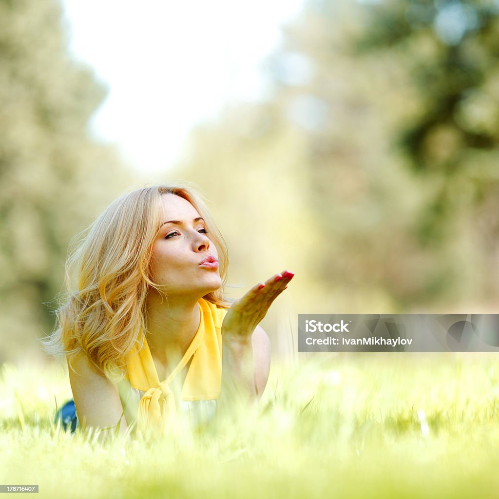 Woman lying on grass Happy young woman lying on grass and blowing kiss Blowing a Kiss Stock Photo