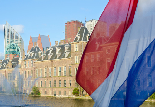Dutch Parliament building (Binnehof) in the Hague with a Dutch flag in the foreground.