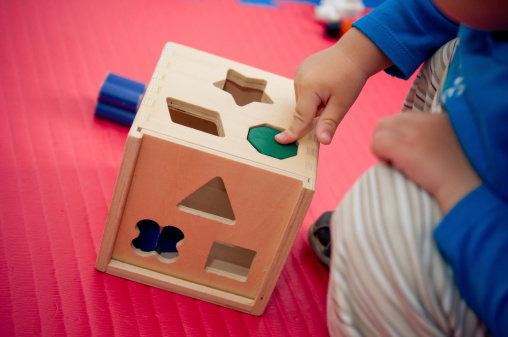 Toddler playing with wooden shape sorter
