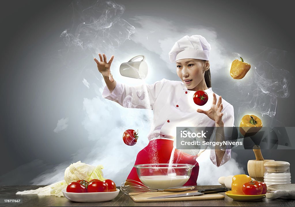 Asian female cooking with magic Asian female cooking with magic against color background Above Stock Photo