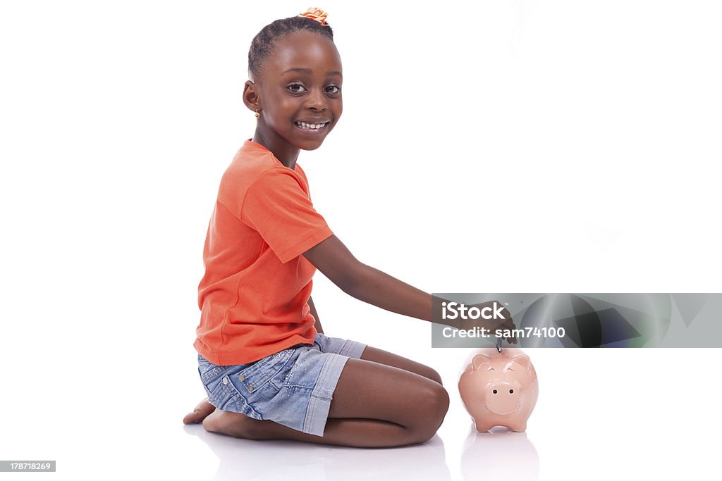 Black girl inserting an euro bill inside a piggy bank Cute little black girl inserting an euro bill inside a piggy bank, isolated on white background - African children Child Stock Photo