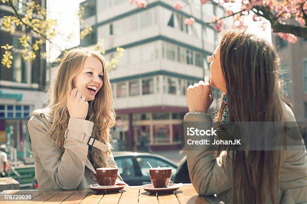 Two Women Laughing Together While Drinking Coffee At A Cafe Stock Photo - Download Image Now