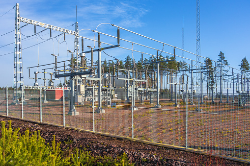 Electrical substation with a fence by a forest