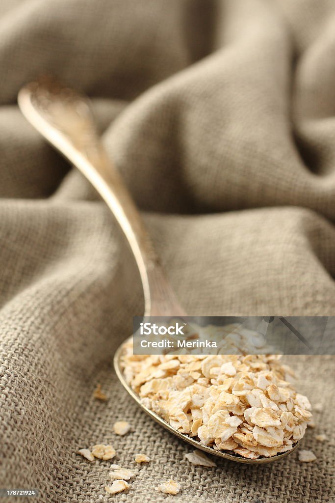 Fiocchi di avena in un cucchiaio su sfondo sackcloth metallo - Foto stock royalty-free di Agricoltura