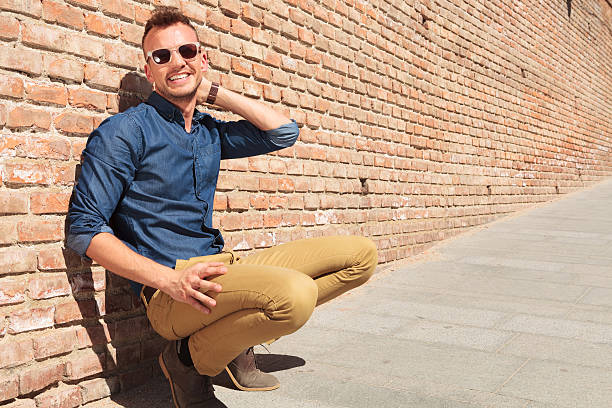 istock casual man crouching by wall and smiling 178722608