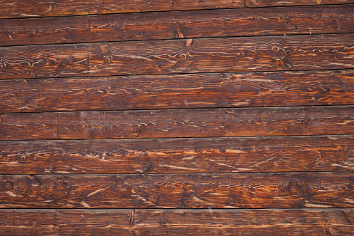 Panorama of an old, brown, weathered wooden wall with two double-rows of nails