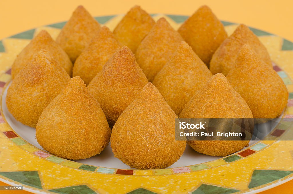 Chicken Coxinha Coxinha de Galinha - Brazilian breaded and deep fried snacks filled with shredded chicken on a colourful plate on a orange background. Coxinha Stock Photo